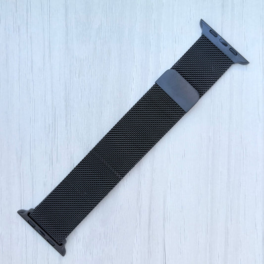 Black Milanese loop for Apple Watch strap on a light blue textured background