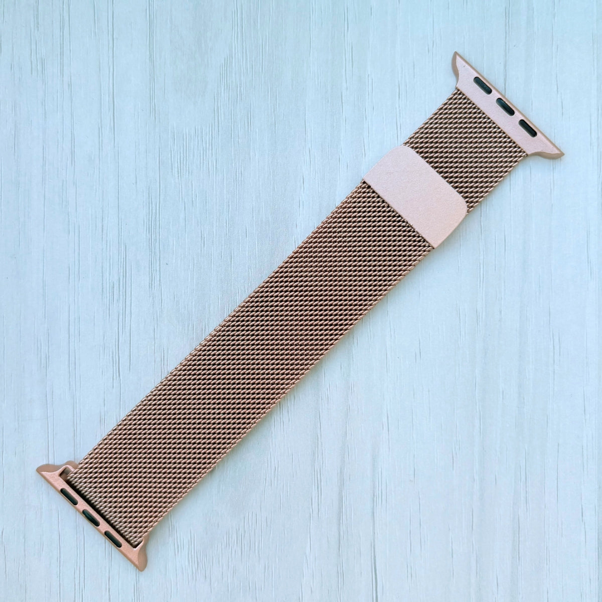 Gold Milanese Loop Strap For Apple watch on a White wooden surface
