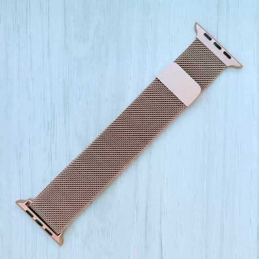 Gold Milanese Loop Strap For Apple watch on a White wooden surface