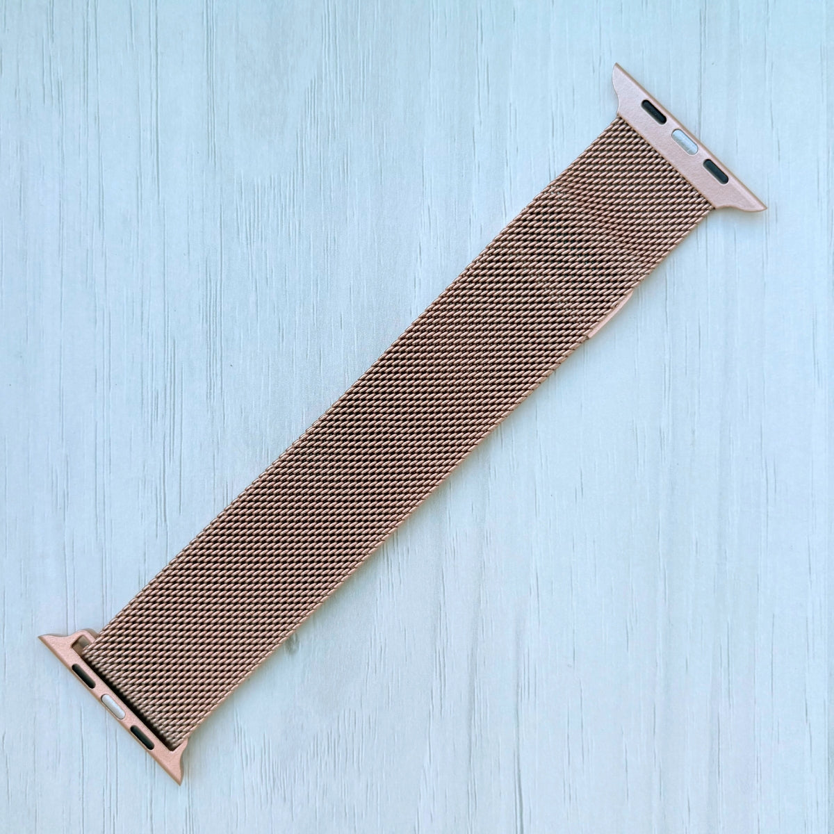 Gold Milanese Loop Strap For Apple watch on a White wooden surface