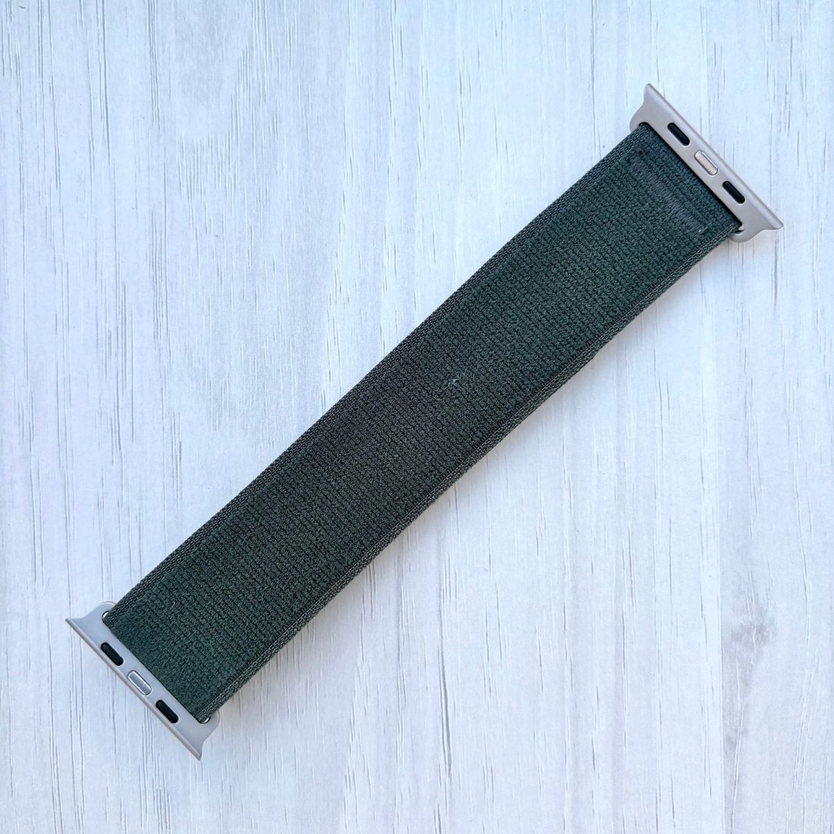 Green Trail loop band with silver finish on a light wooden surface