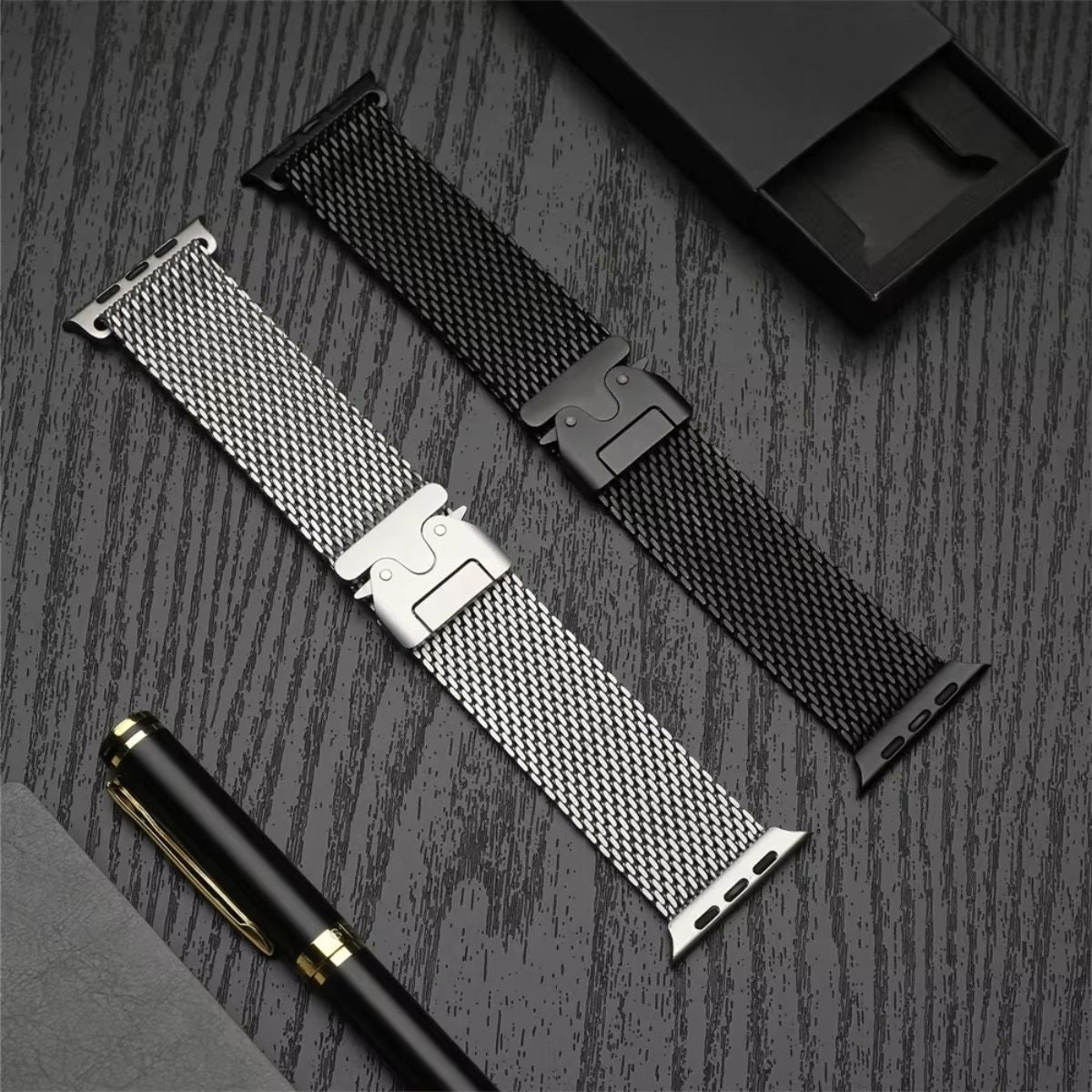 Two Milanese loop Apple Watch bands in black and silver laid out on a dark wooden surface, highlighting their premium stainless steel mesh construction