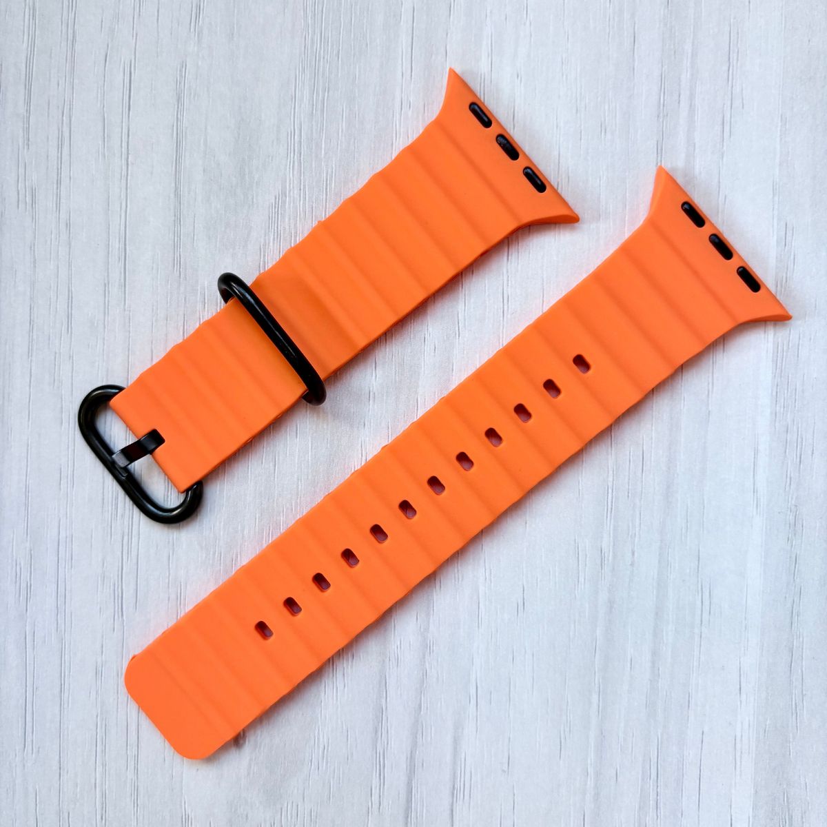 Apple watch Ocean Band in Orange with black buckle on a White wooden background