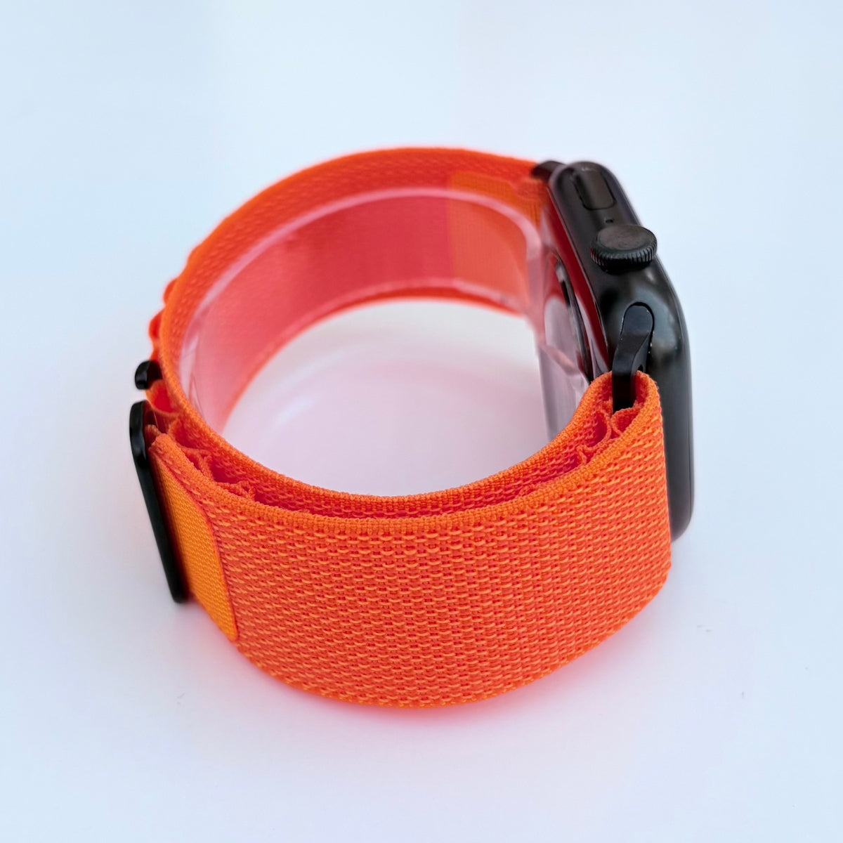 Side view Apple watch series 11 with Orange Alpine loop band with black connectors and buckle on a white background