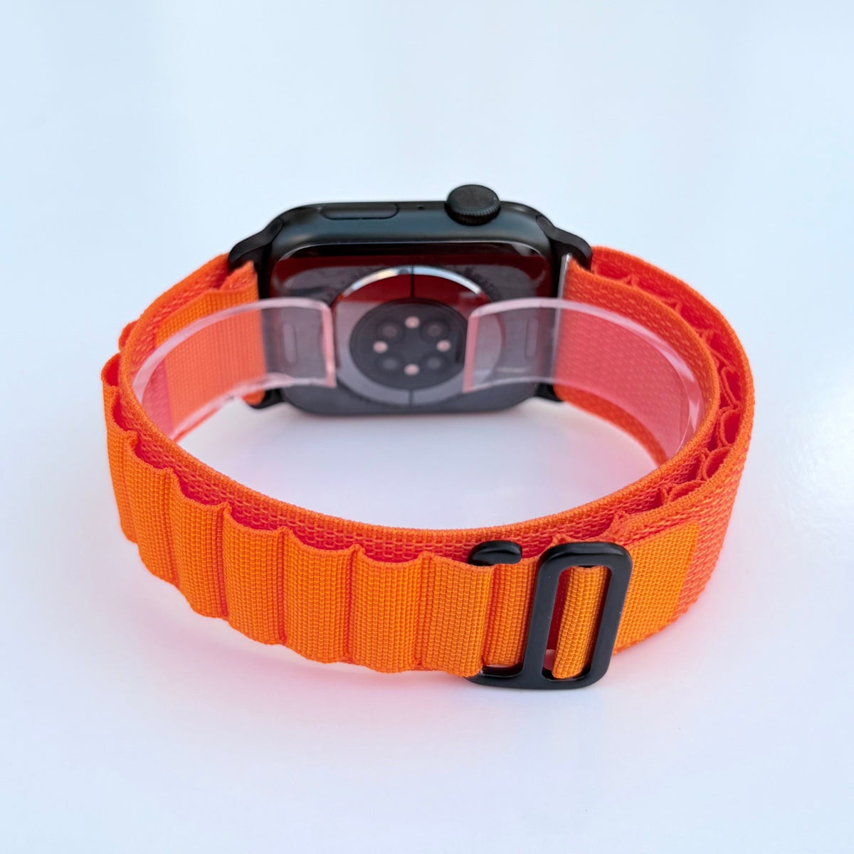 Back view Apple watch series 11 with Orange Alpine loop band with black connectors and buckle on a white background