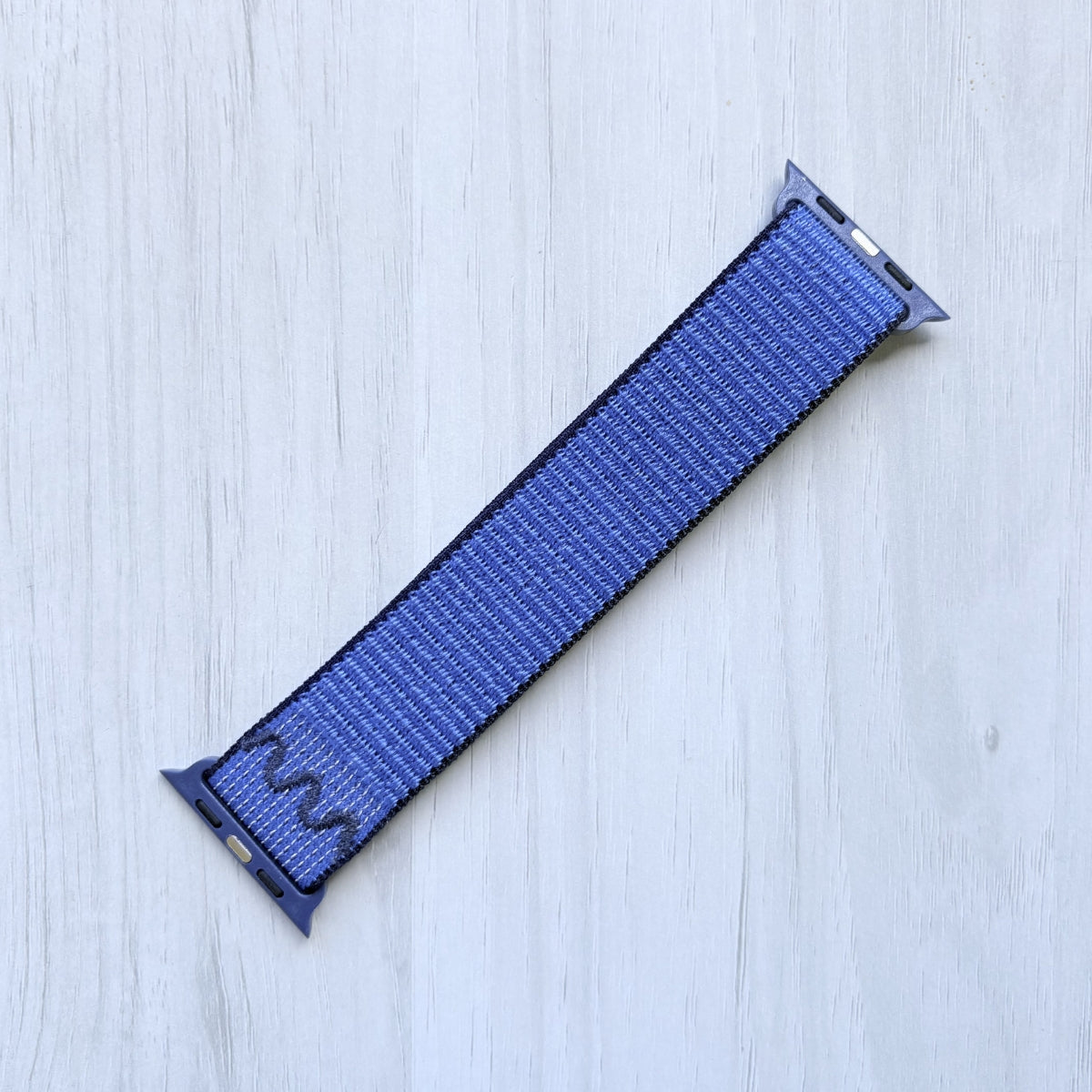 Blue Ribbon Nike sport loop band for apple watch on a white background, back side.