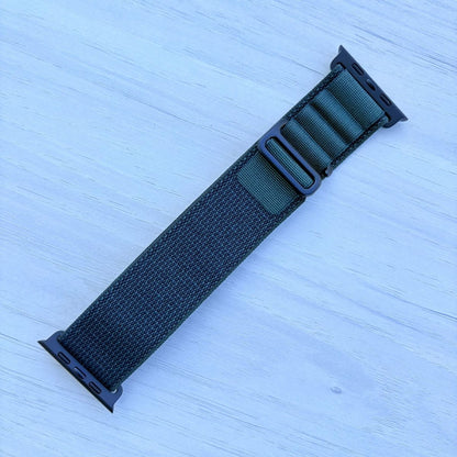 Dark green Alpine loop Band for apple watch with Black finish on a white wooden background front view