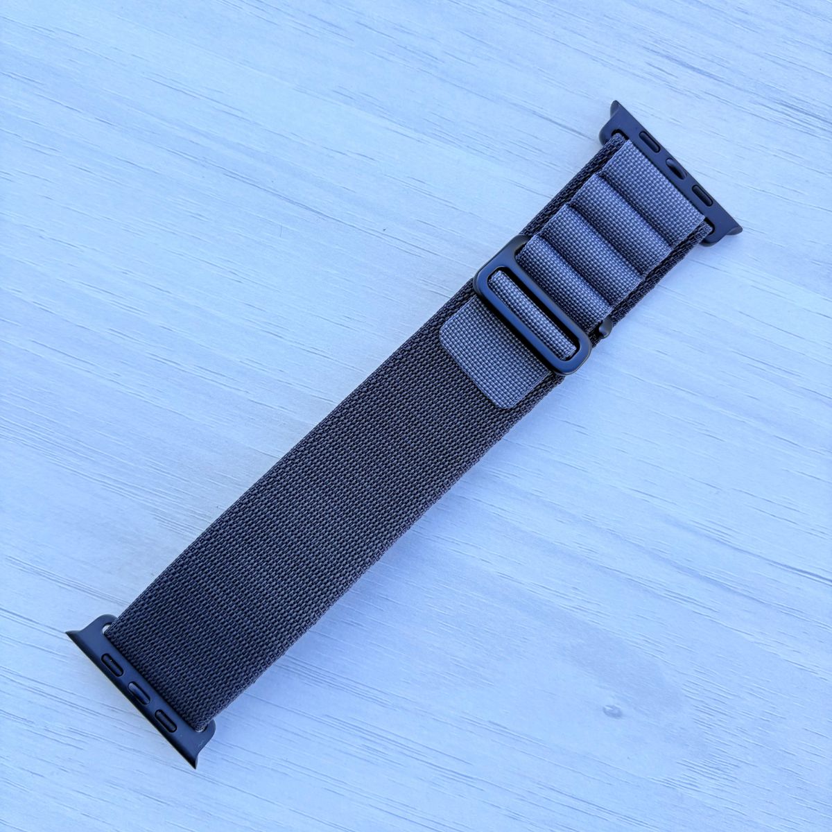 Dark gray Alpine loop Band for apple watch with Black finish on a white wooden background front view