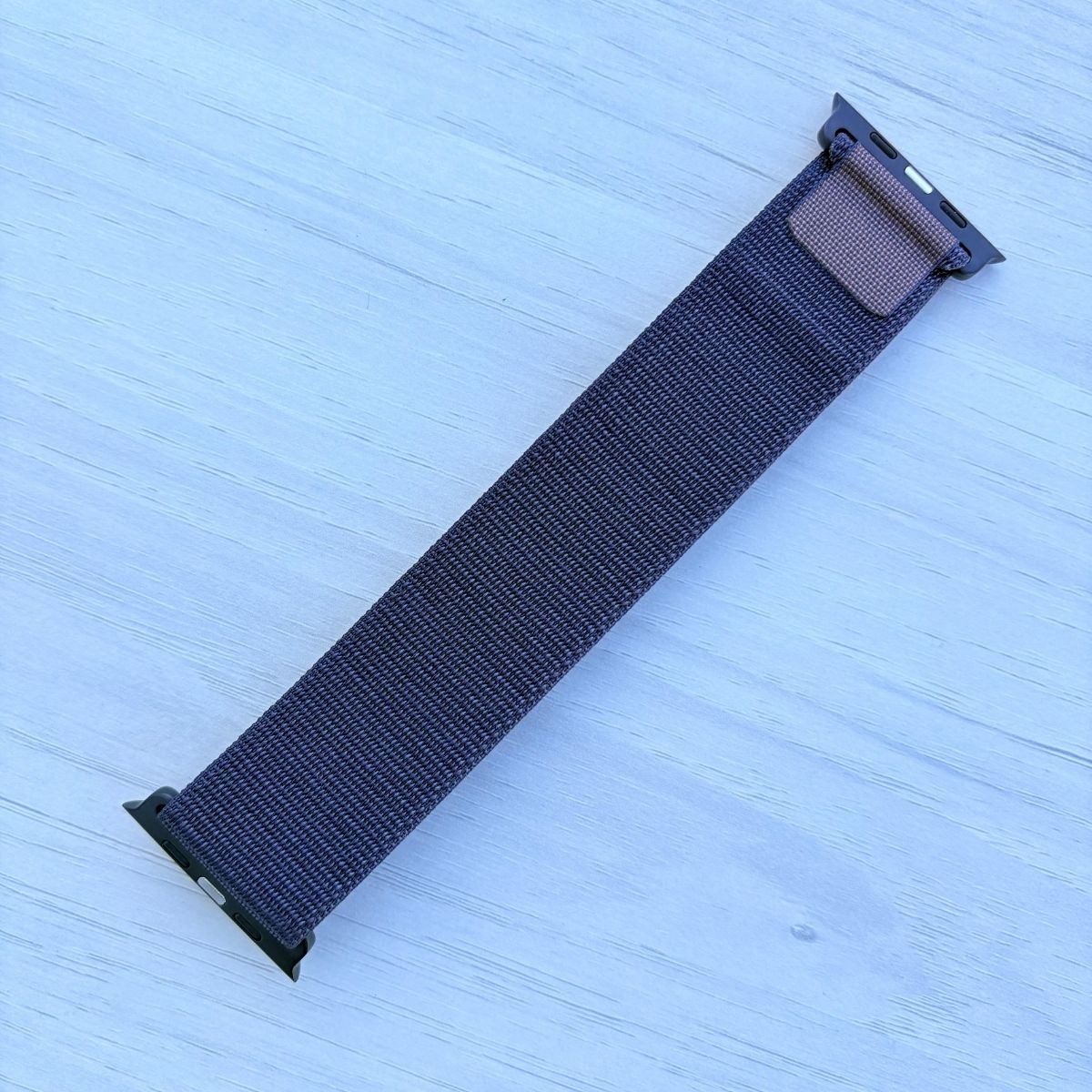 Indigo Alpine loop Band for apple watch with Black finish on a white wooden background back view