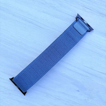 Light blue Alpine loop Band for apple watch with Black finish on a white wooden background back view