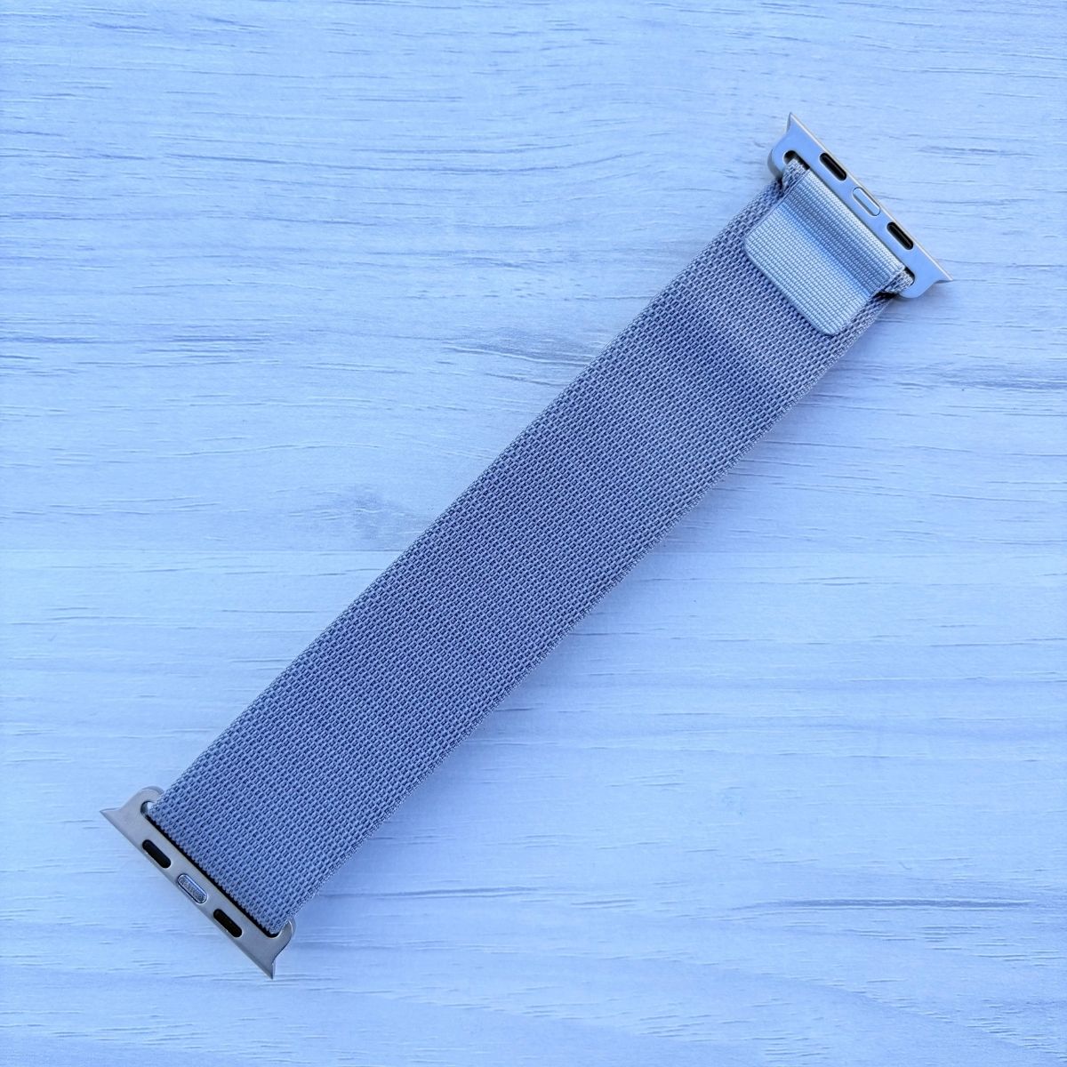 Light Gray Alpine Loop nylon band with titanium finish back view in a light white wooden background