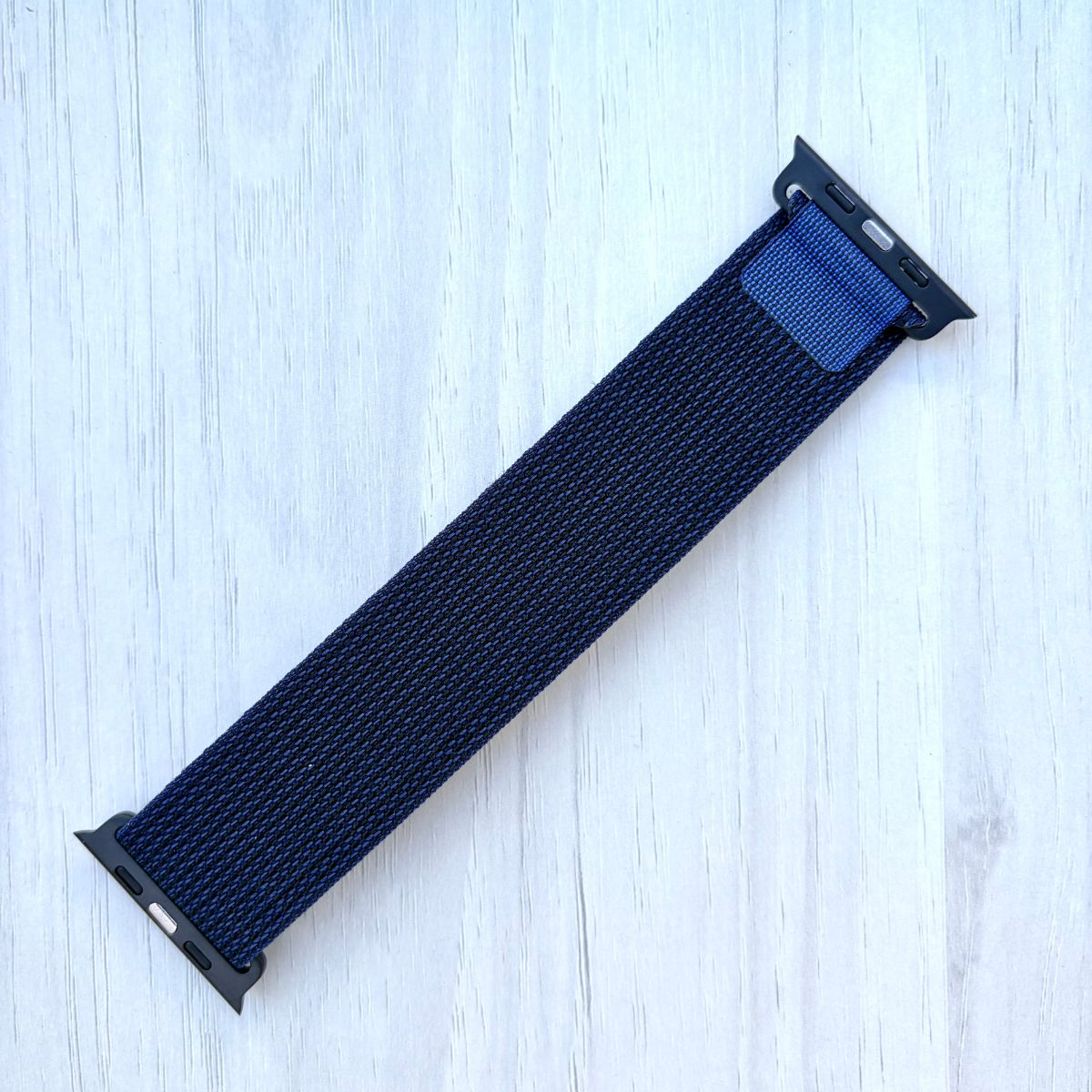 Navy blue Apple watch strap on a light wooden surface