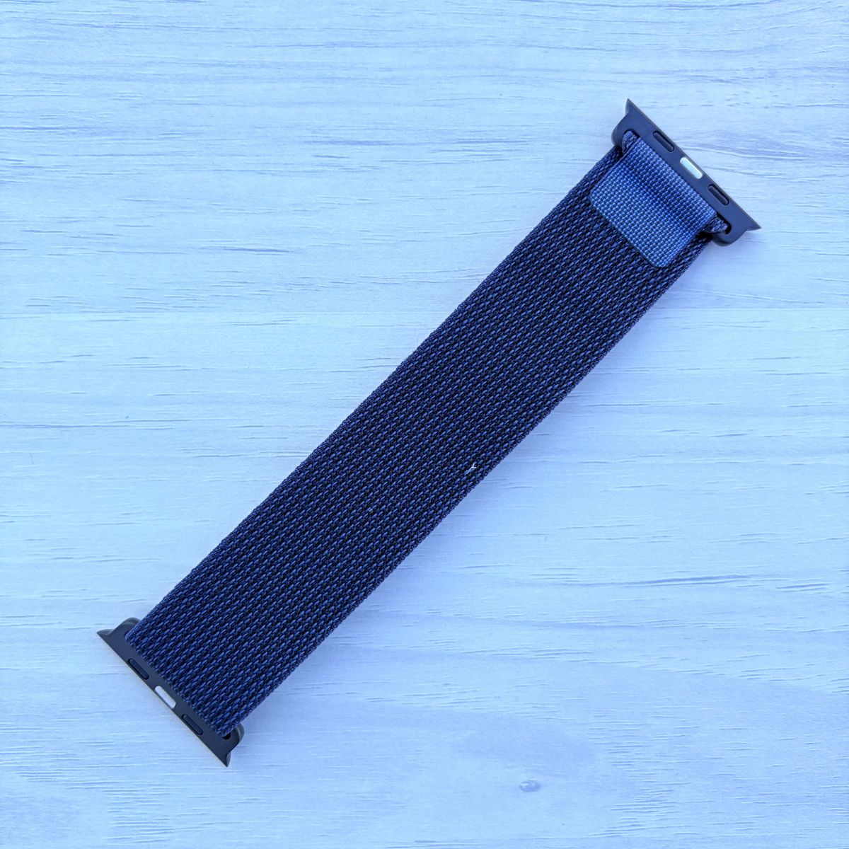 Navy blue Alpine loop Band for apple watch with Black finish on a white wooden background back view