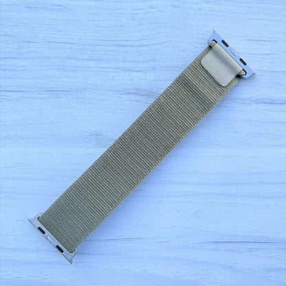 Olive Alpine Loop nylon band with titanium finish back view in a light white wooden background