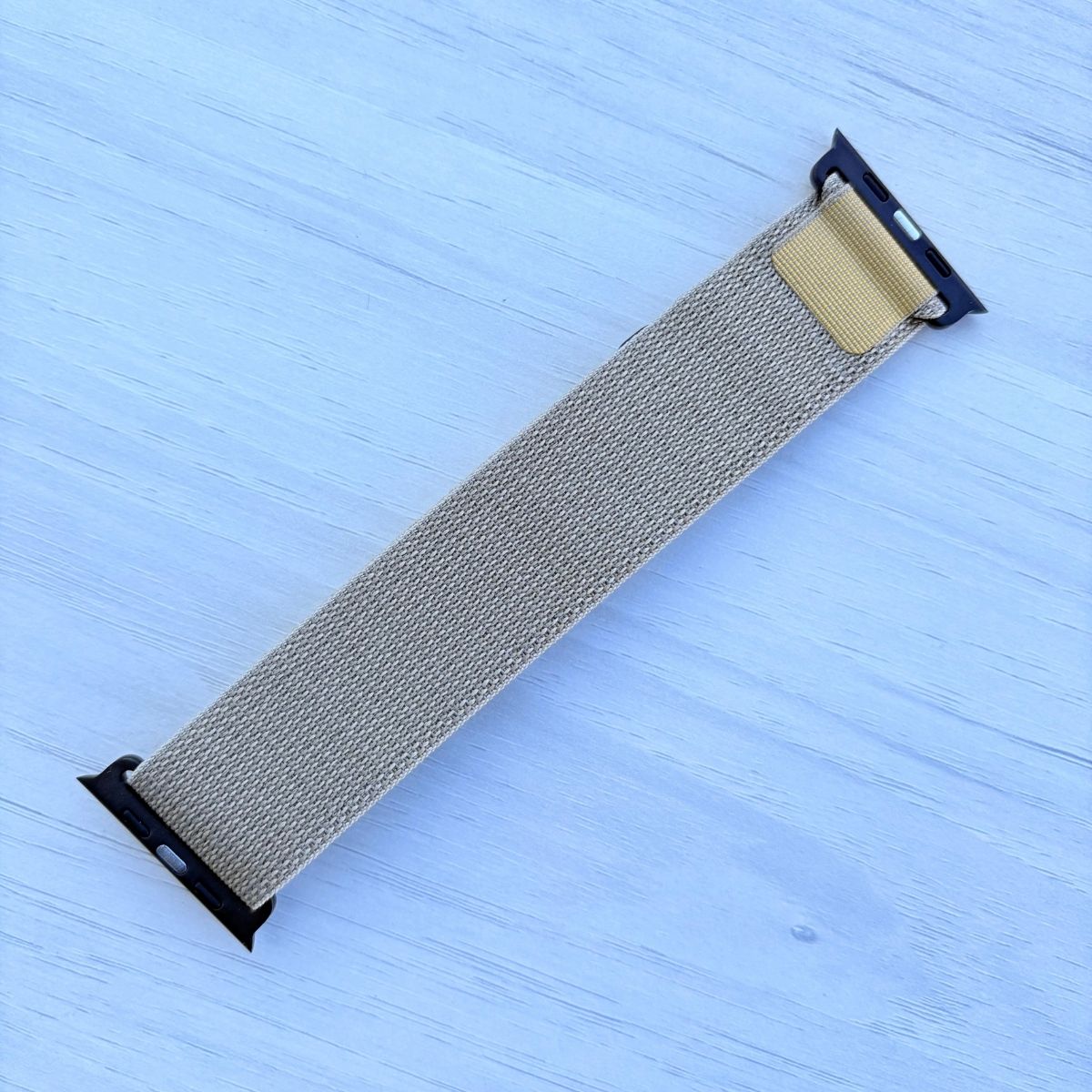 Tan Alpine loop Band for apple watch with Black finish on a white wooden background back view