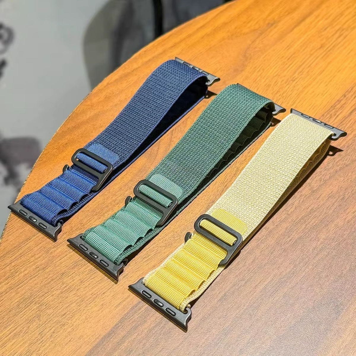 Alpine Loop Apple Watch bands in Navy, Tan, and Dark Green colors side by side