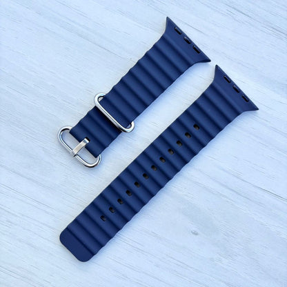 Black Ocean band Apple watch strap with silver buckle on a light wooden surface