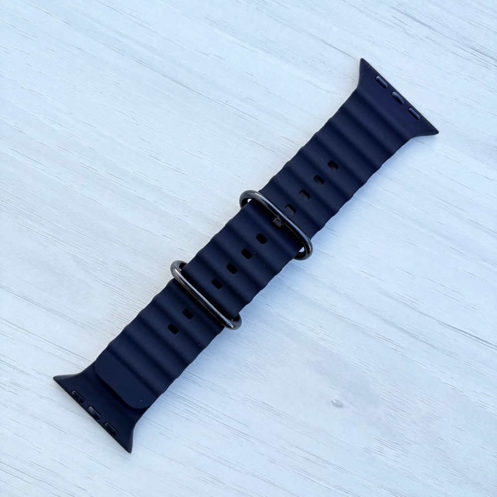 Black Ocean band Apple watch strap with black buckle front view on a light wooden surface