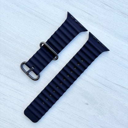 Black Ocean band Apple watch strap with black buckle on a light wooden surface