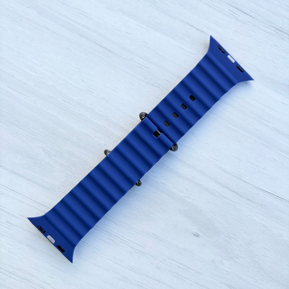 Ocean band for Apple watch in midnight blue with Black buckle on a light wooden surface Back view.