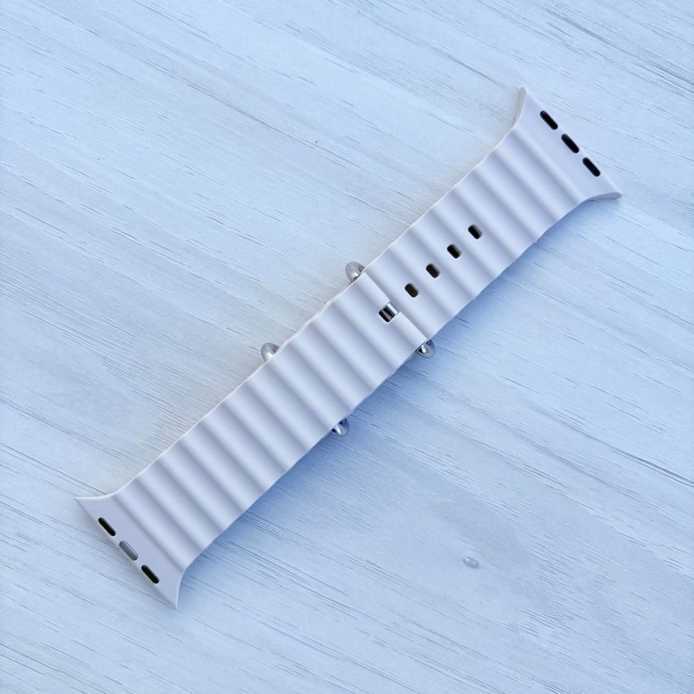 Ocean Band for Apple Watch in Starlight with Silver Buckle, Back View on Light Wooden Surface