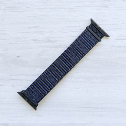 Ink Sport Loop Apple Watch Band with woven nylon design displayed on a light wooden surface, front view.